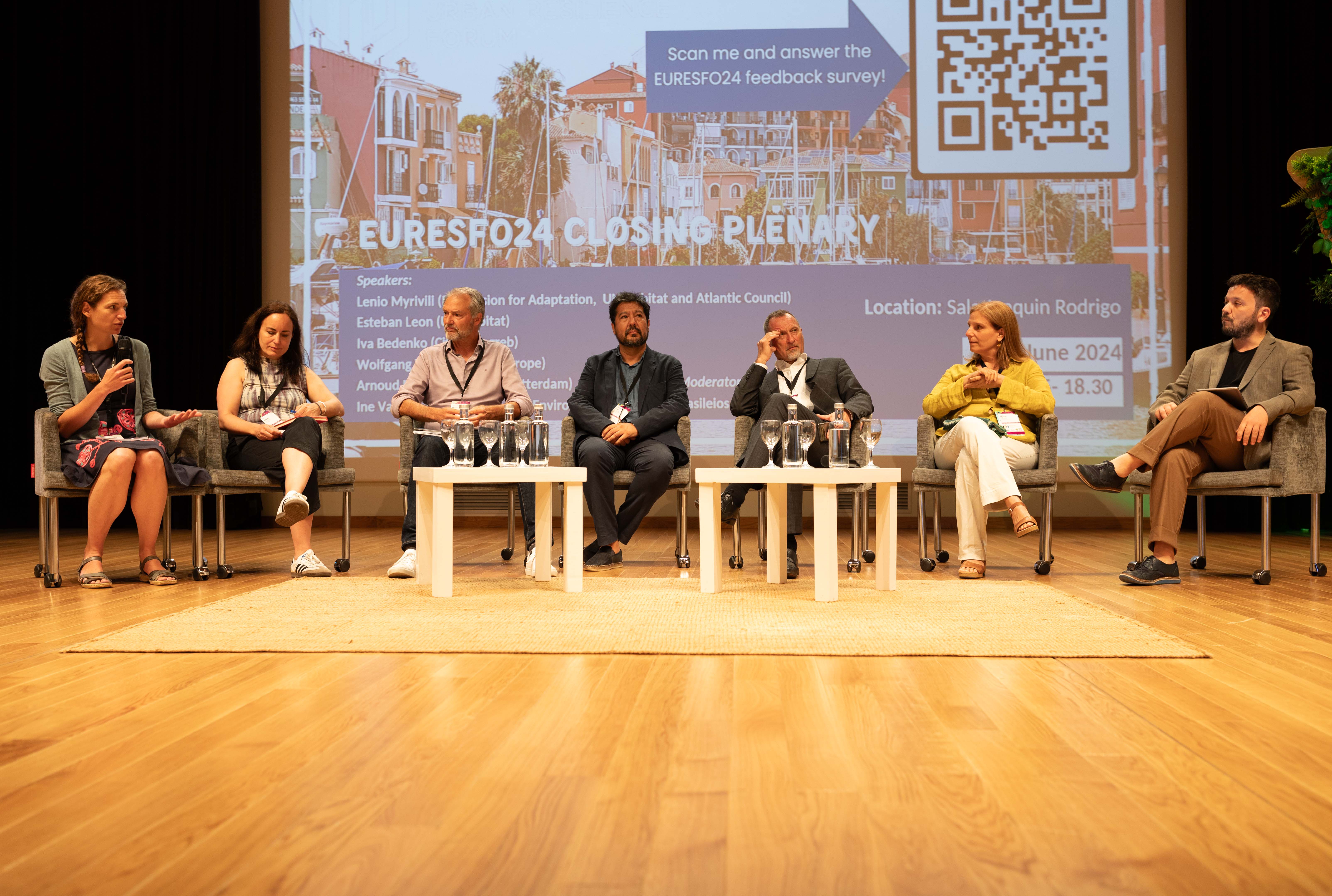 a group of speakers sitting on chairs on the stage of the European Urban Resilience Forum  