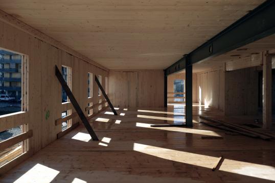 Wooden-floored building interior with windows. 