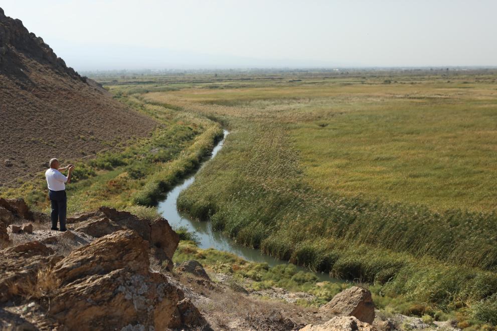 Man looks out on river against a vast landscape