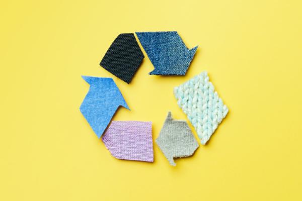 Yellow background with recycling symbol made of textiles.