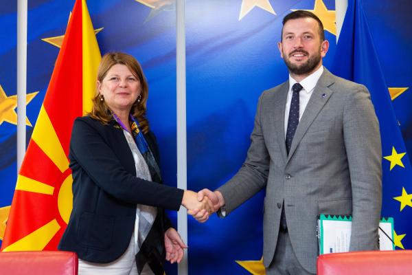 Virginijus Sinkevičius and Kaja Sukova shaking hands in front of North Macedonia and EU flags.